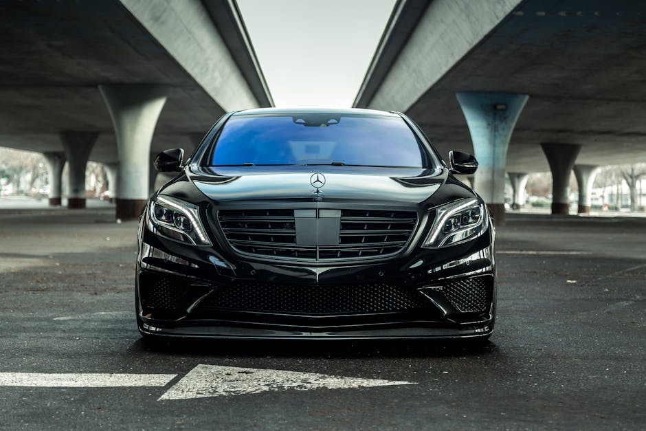 Sleek black luxury car parked outdoors under a modern urban bridge in Sacramento