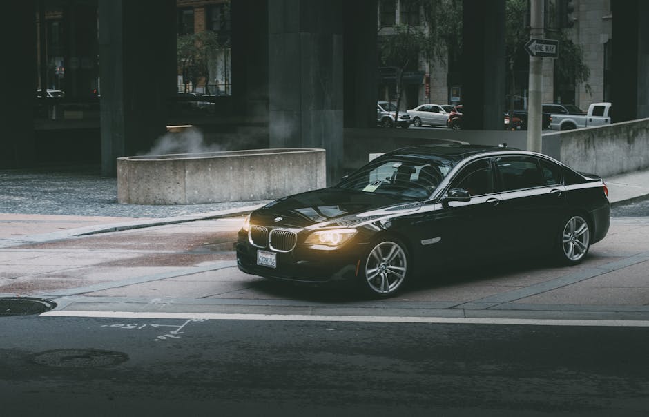A luxury black car navigating city streets at twilight, showcasing modern city life and design
